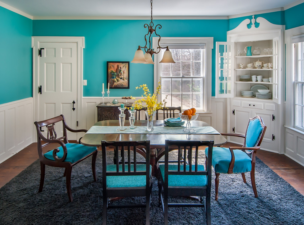Cette photo montre une salle à manger éclectique fermée et de taille moyenne avec un mur bleu et parquet foncé.