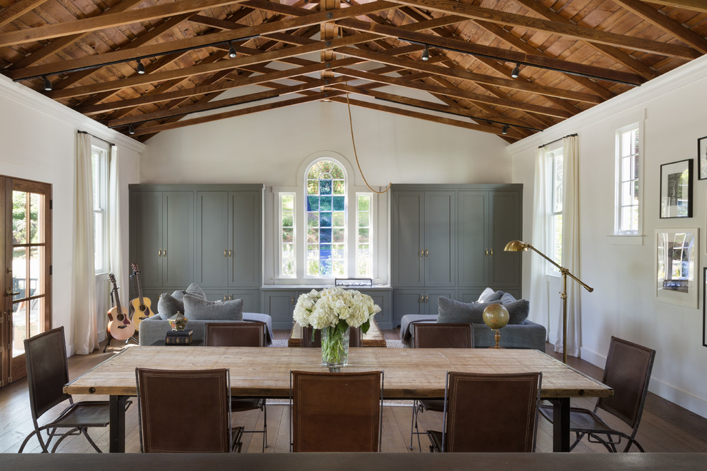 Inspiration pour une salle à manger ouverte sur le salon traditionnelle avec un mur blanc, un sol en bois brun et aucune cheminée.