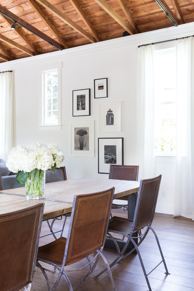 Cette image montre une salle à manger ouverte sur le salon traditionnelle avec un mur blanc et un sol en bois brun.