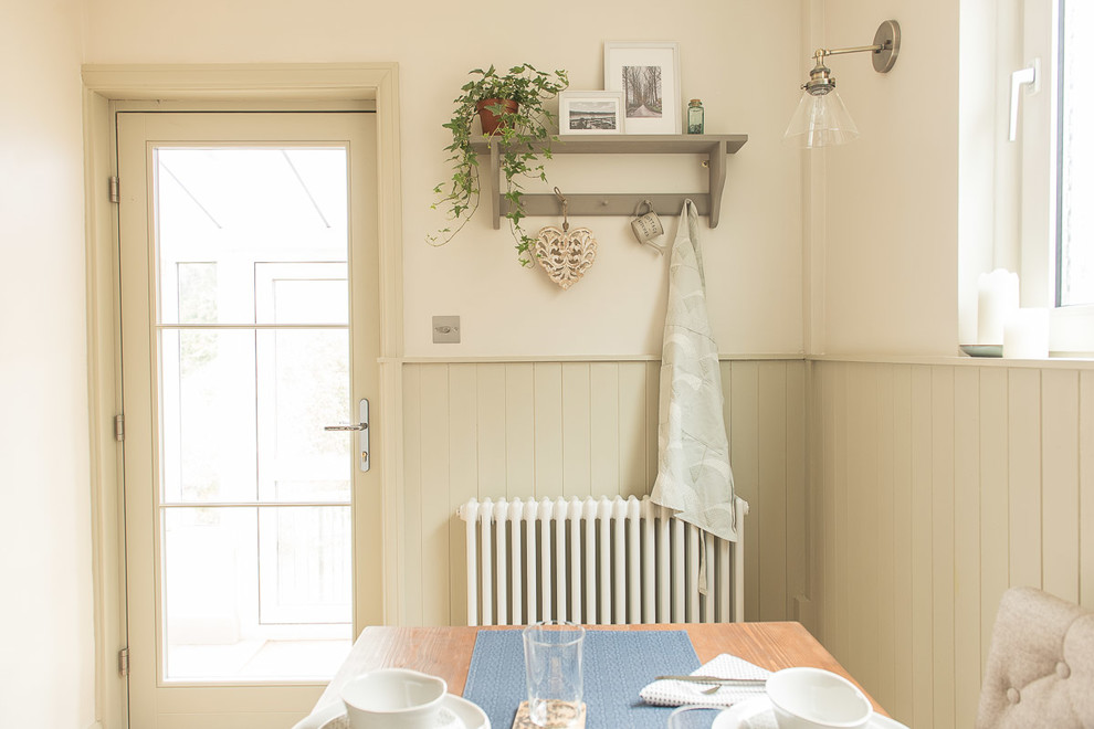 Foto di una piccola sala da pranzo aperta verso la cucina country con pareti beige, pavimento in laminato, nessun camino e pavimento marrone