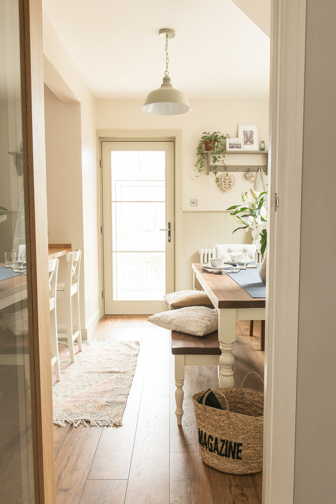Foto di una piccola sala da pranzo aperta verso la cucina country con pareti beige, pavimento in laminato, nessun camino e pavimento marrone