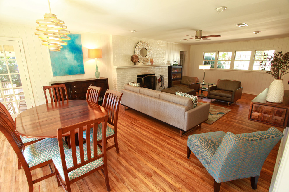 Exemple d'une petite salle à manger ouverte sur le salon tendance avec un mur blanc, un sol en bois brun, une cheminée standard et un manteau de cheminée en brique.