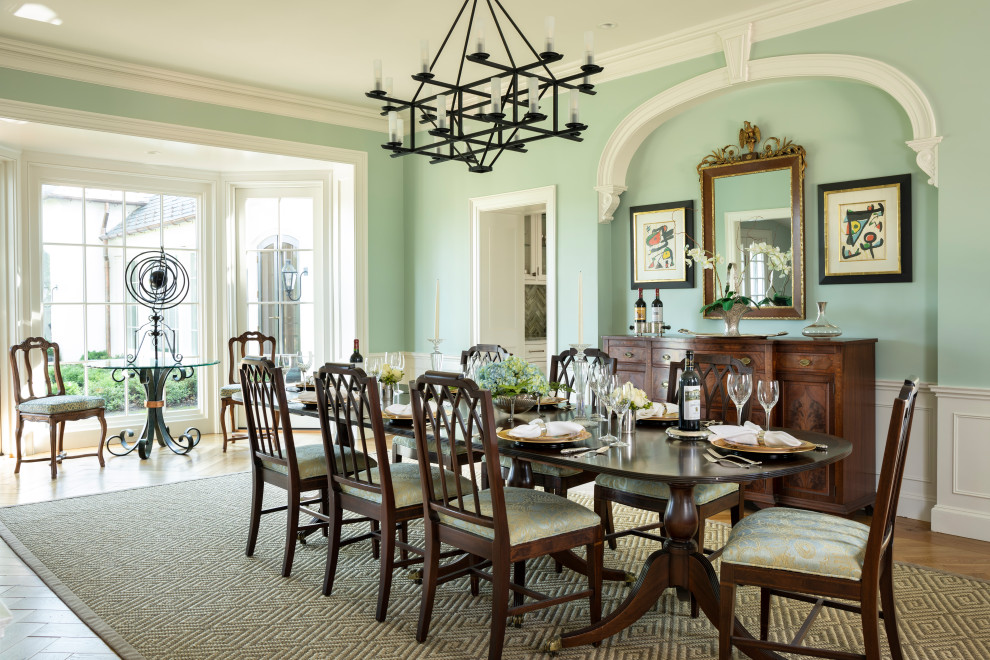 На фото: столовая в классическом стиле с зелеными стенами, паркетным полом среднего тона, коричневым полом и панелями на стенах