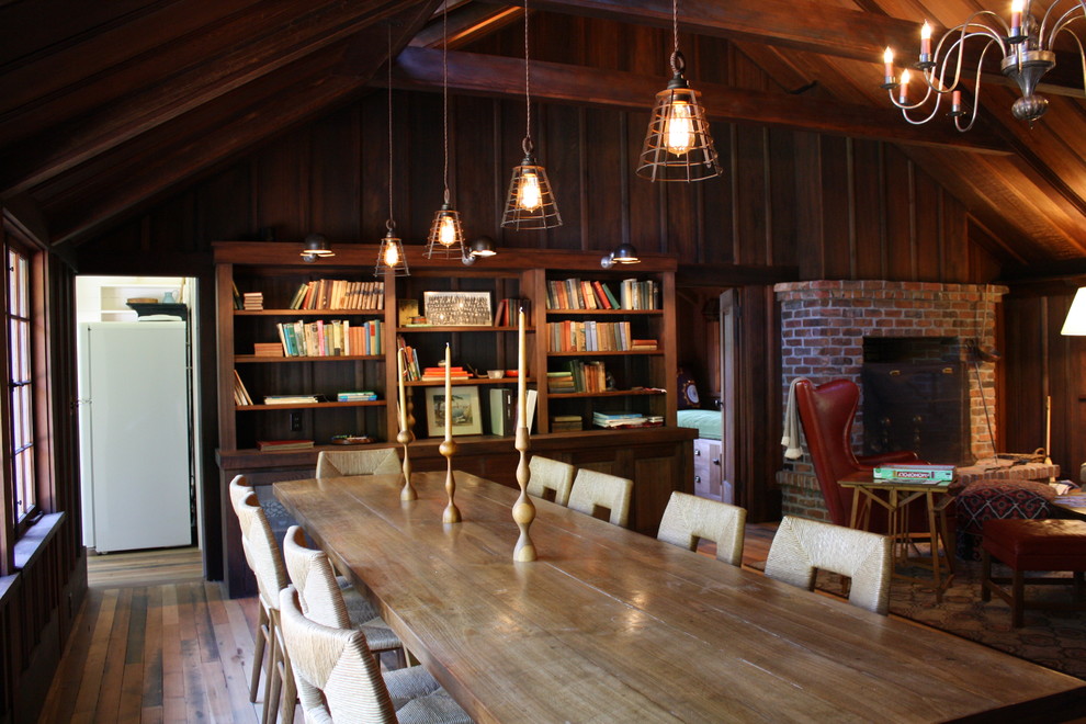 Idées déco pour une grande salle à manger ouverte sur le salon montagne avec un mur marron, un sol en bois brun, une cheminée standard, un manteau de cheminée en brique et un sol marron.