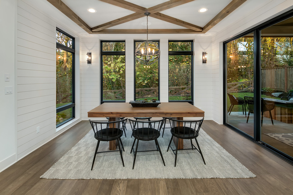 Modelo de comedor de estilo de casa de campo grande abierto sin chimenea con paredes blancas, suelo de madera en tonos medios y suelo marrón