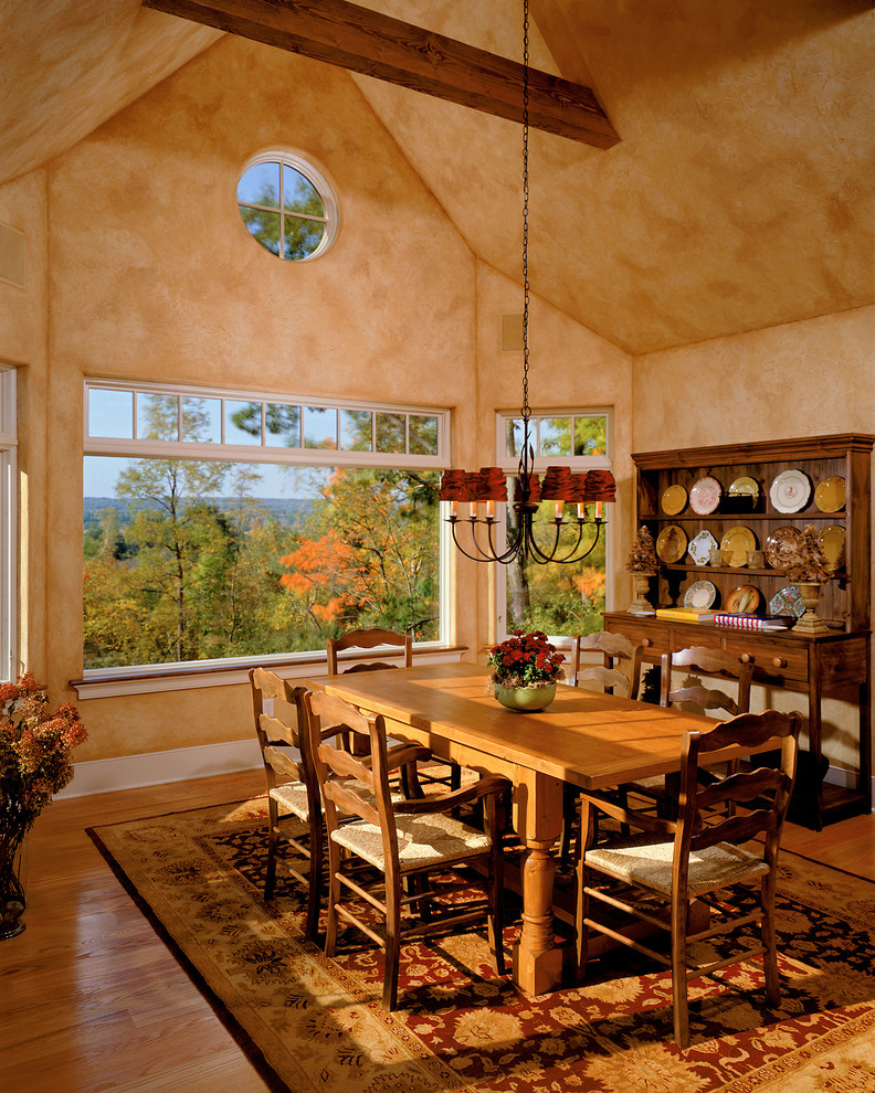 Cette image montre une salle à manger traditionnelle avec un mur orange et un sol en bois brun.