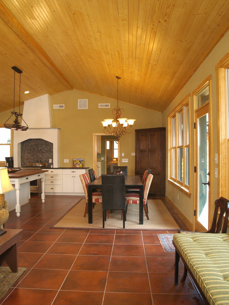 Foto di una sala da pranzo aperta verso la cucina country di medie dimensioni con pareti beige, pavimento in terracotta, nessun camino e pavimento rosso