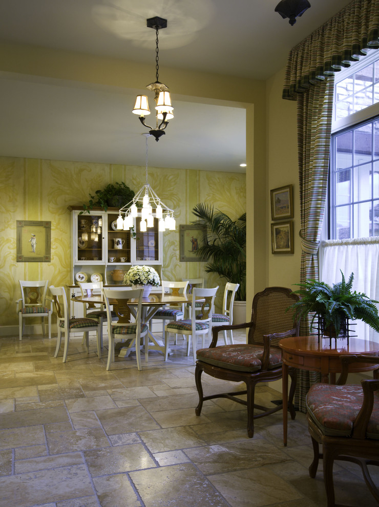 Réalisation d'une rideau de salle à manger méditerranéenne avec un mur jaune et un sol en travertin.