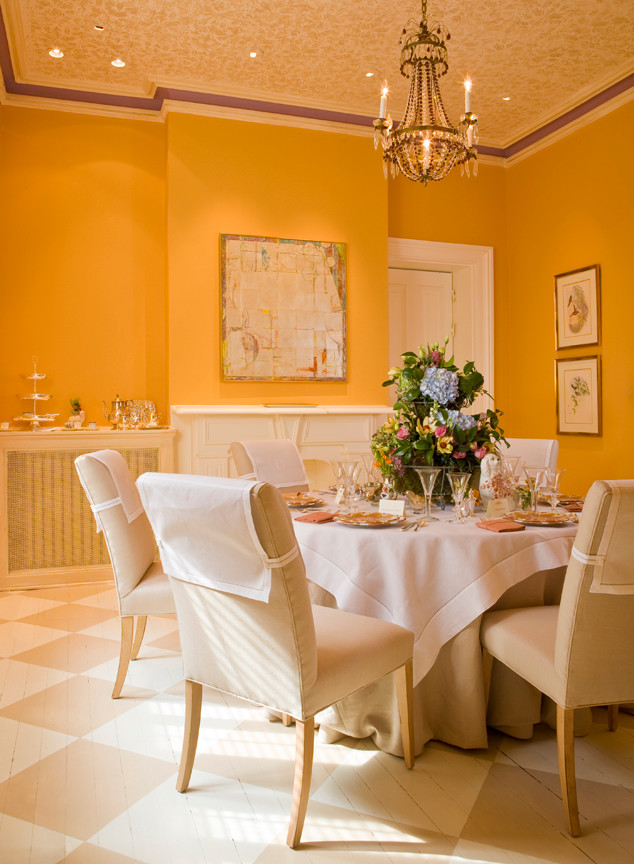 На фото: гостиная-столовая среднего размера в классическом стиле с деревянным полом, стандартным камином, фасадом камина из штукатурки и желтыми стенами