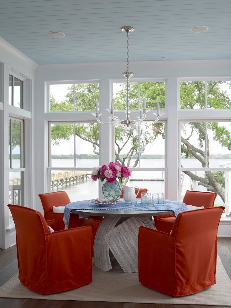 Idées déco pour une salle à manger ouverte sur la cuisine bord de mer avec un mur blanc et un sol en bois brun.