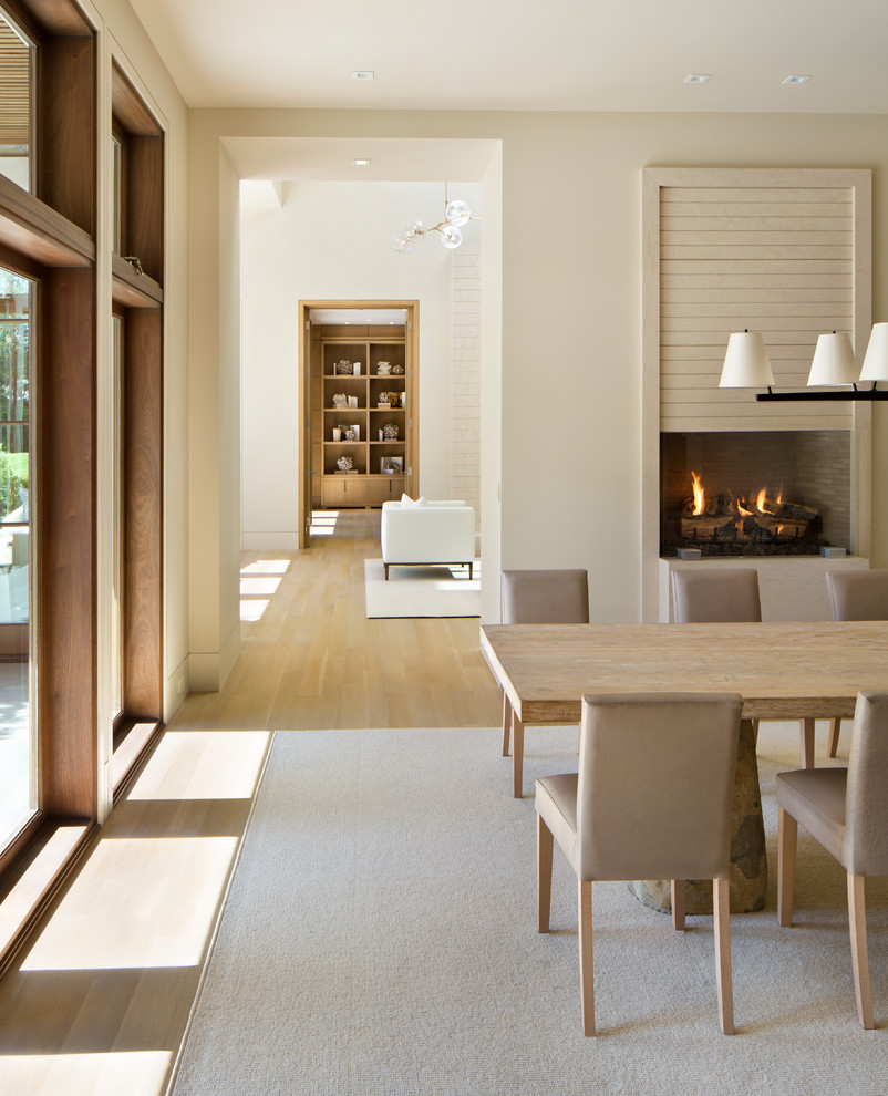 Immagine di una sala da pranzo minimal chiusa con pareti bianche, pavimento in legno massello medio e camino classico
