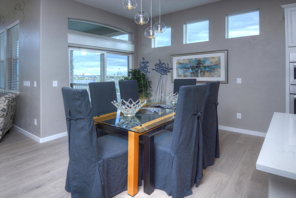 Cette image montre une salle à manger ouverte sur la cuisine design avec un mur gris et parquet clair.