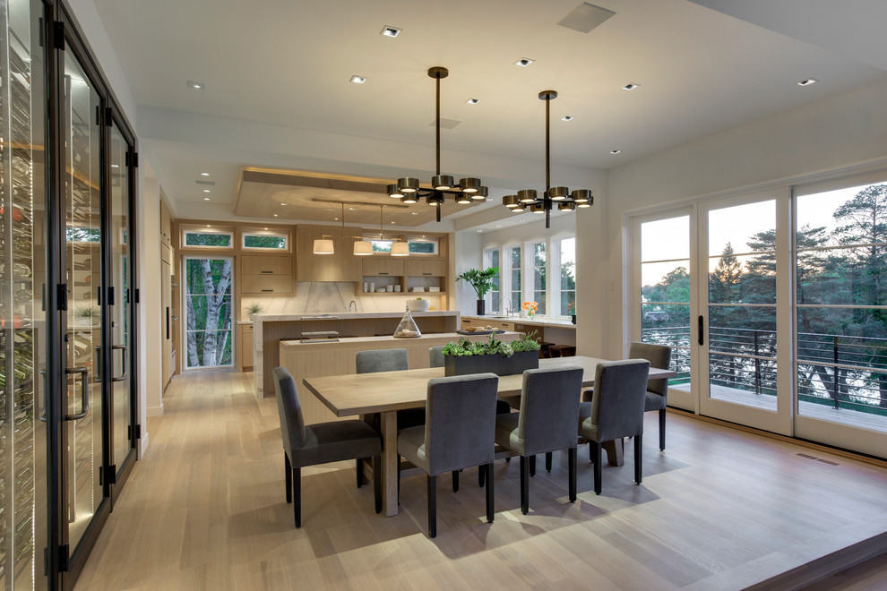 Expansive modern open plan dining room in Minneapolis with white walls and light hardwood flooring.