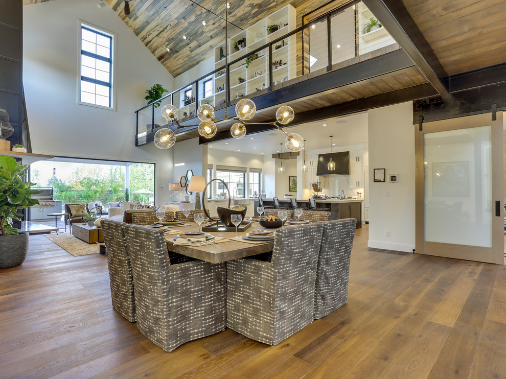 Inspiration for an expansive farmhouse open plan dining room in Portland with white walls, medium hardwood flooring, a standard fireplace, a metal fireplace surround and brown floors.