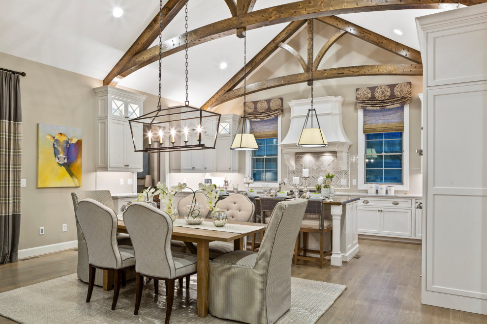 Foto di una sala da pranzo aperta verso la cucina classica con pareti beige, pavimento in legno massello medio, pavimento marrone e soffitto a volta