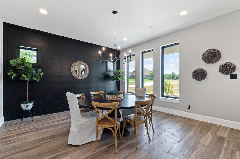 Immagine di una sala da pranzo country chiusa e di medie dimensioni con pareti grigie, pavimento in legno massello medio, pavimento marrone e pareti in perlinato