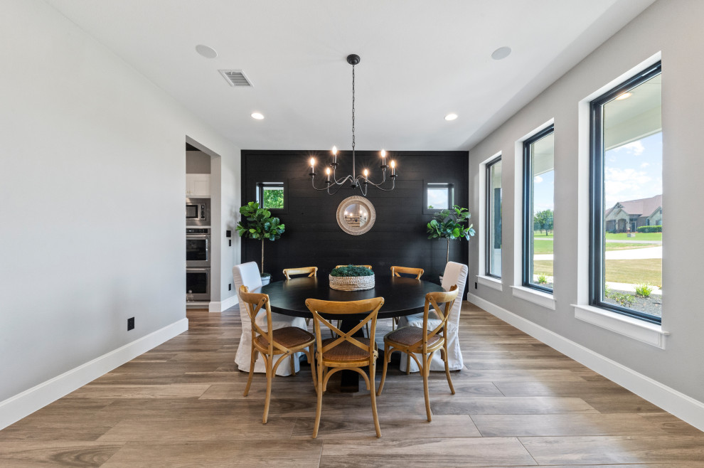 Geschlossenes, Mittelgroßes Landhausstil Esszimmer mit grauer Wandfarbe, braunem Holzboden, braunem Boden und Holzdielenwänden in Dallas