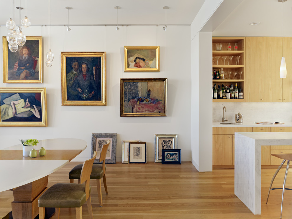 Aménagement d'une salle à manger ouverte sur la cuisine contemporaine avec un mur blanc et un sol en bois brun.