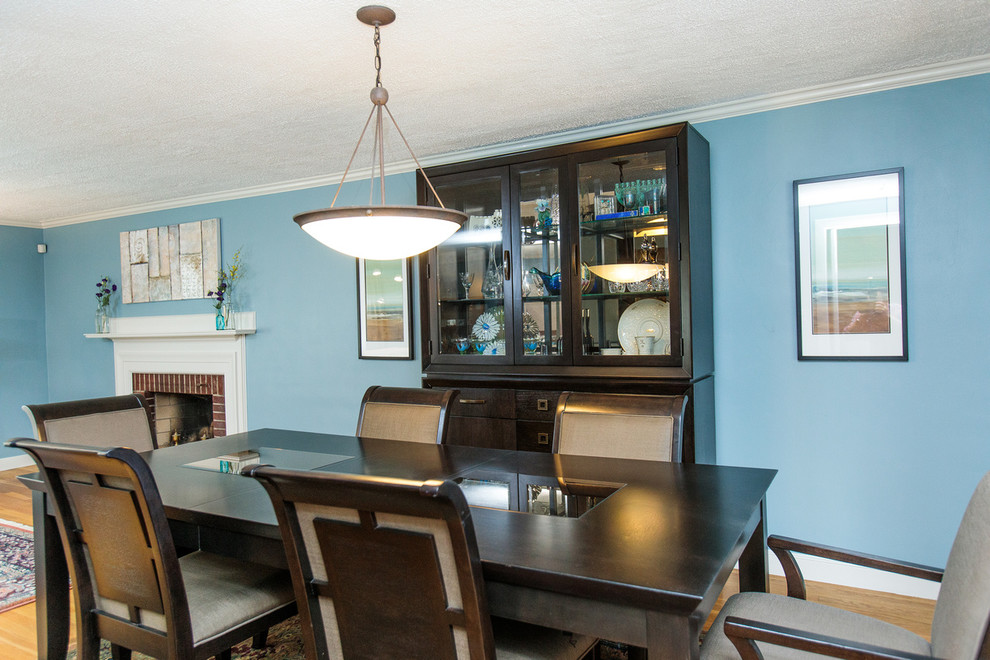 Esempio di una sala da pranzo aperta verso il soggiorno minimal di medie dimensioni con pareti blu, pavimento in legno massello medio, camino classico e cornice del camino in mattoni