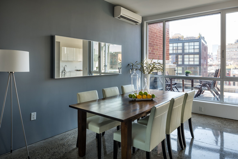 Cette image montre une salle à manger ouverte sur la cuisine minimaliste de taille moyenne avec un mur gris et sol en béton ciré.