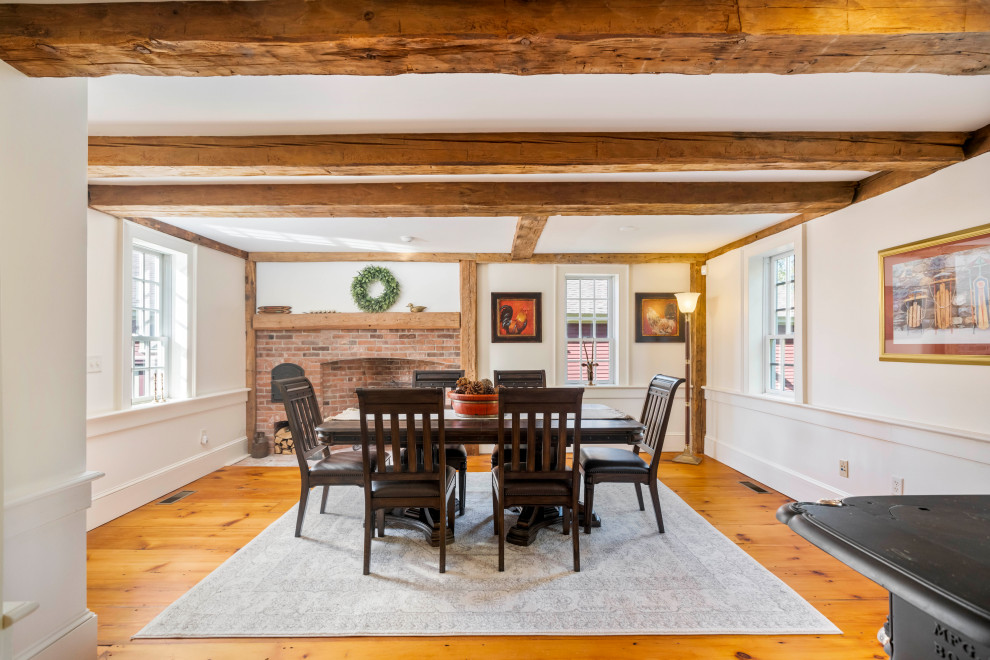 This is an example of a farmhouse enclosed dining room in Boston with white walls, medium hardwood flooring, brown floors, exposed beams and wainscoting.