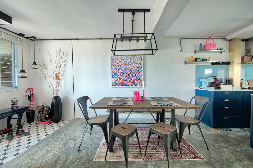 Immagine di una sala da pranzo aperta verso la cucina bohémian con pareti bianche, pavimento in cemento e nessun camino