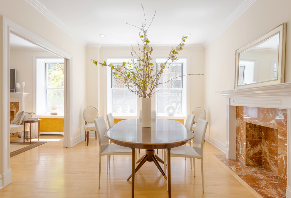 Immagine di una sala da pranzo aperta verso il soggiorno minimal di medie dimensioni con pareti beige, parquet chiaro e camino classico