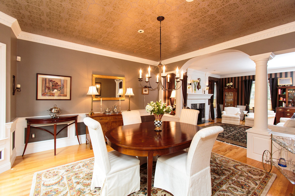 На фото: большая гостиная-столовая в классическом стиле с коричневыми стенами и паркетным полом среднего тона с