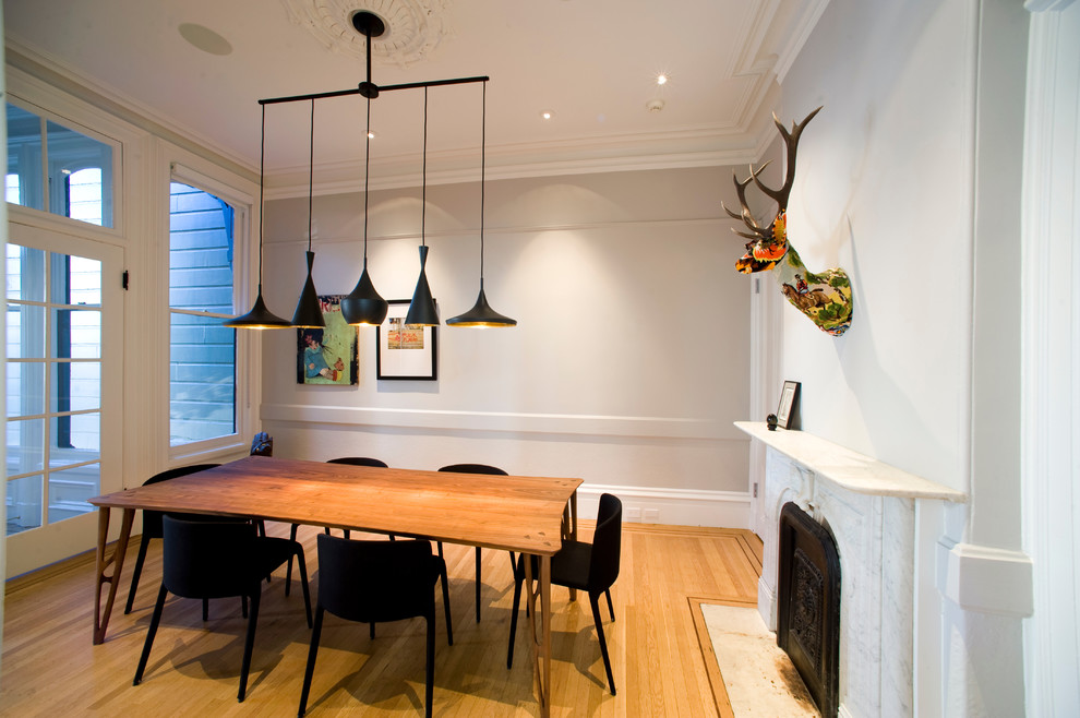 Aménagement d'une salle à manger contemporaine avec un mur gris, un sol en bois brun et une cheminée standard.