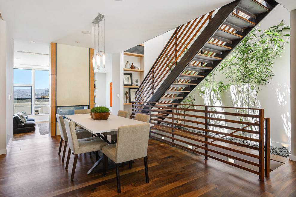 Inspiration pour une salle à manger design avec un mur blanc, un sol en bois brun et une cheminée double-face.