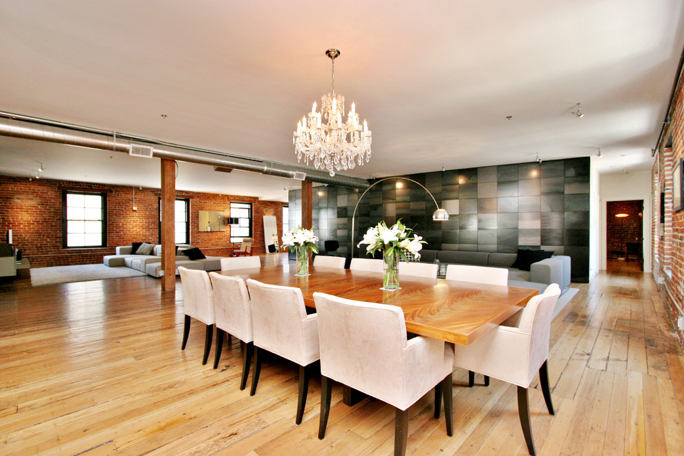 Immagine di una sala da pranzo industriale con pavimento in legno massello medio