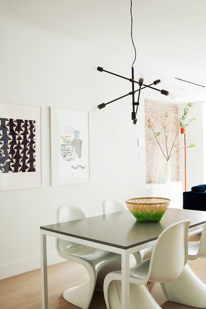 Immagine di una sala da pranzo aperta verso il soggiorno minimalista di medie dimensioni con pareti bianche e parquet chiaro