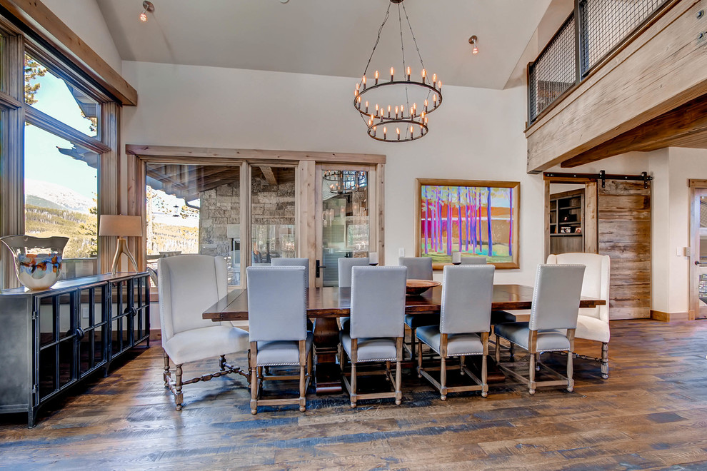 This is an example of a rustic dining room in Denver with white walls, dark hardwood flooring and feature lighting.