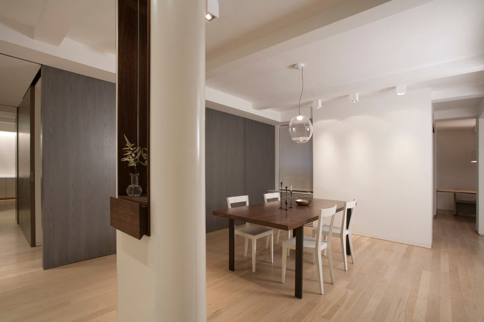 Inspiration pour une salle à manger design avec un mur blanc et un sol en bois brun.