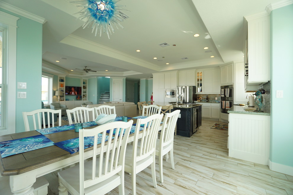 Immagine di una sala da pranzo aperta verso il soggiorno stile marinaro di medie dimensioni con pareti blu, pavimento in gres porcellanato e nessun camino