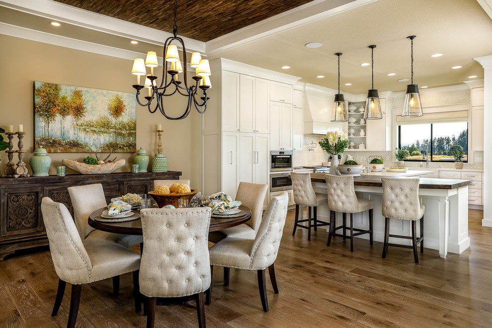 Kitchen/dining room combo - large farmhouse medium tone wood floor and beige floor kitchen/dining room combo idea in Portland with beige walls, a standard fireplace and a stone fireplace