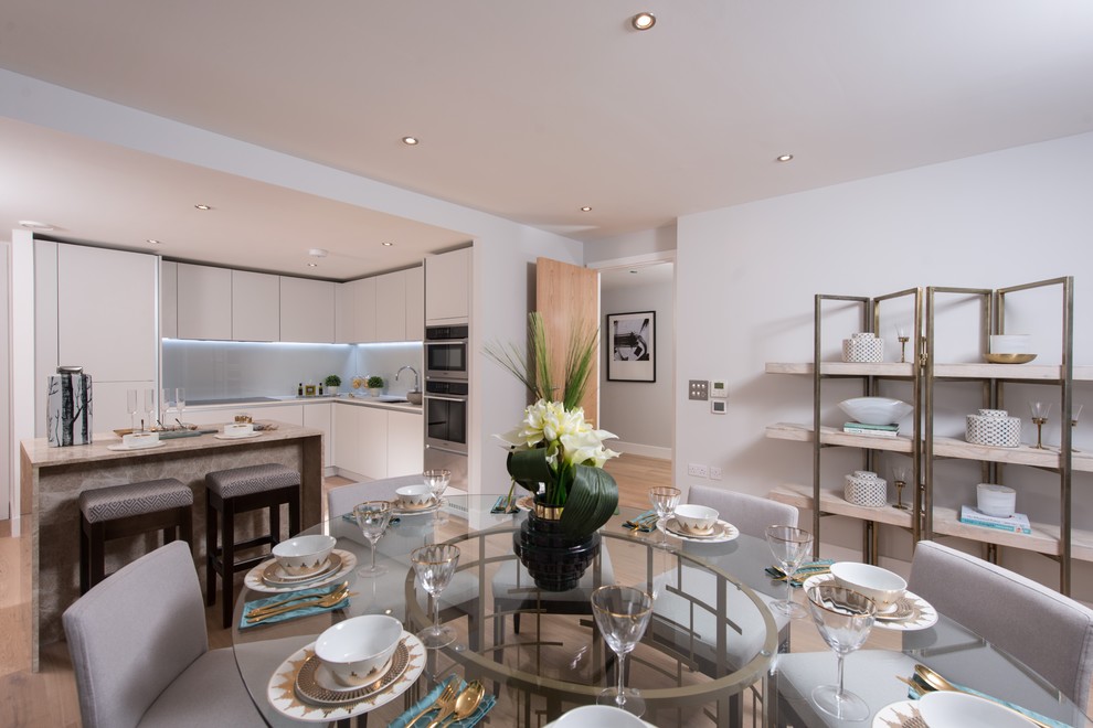 Immagine di una sala da pranzo aperta verso la cucina contemporanea di medie dimensioni con pareti bianche, parquet chiaro e pavimento beige