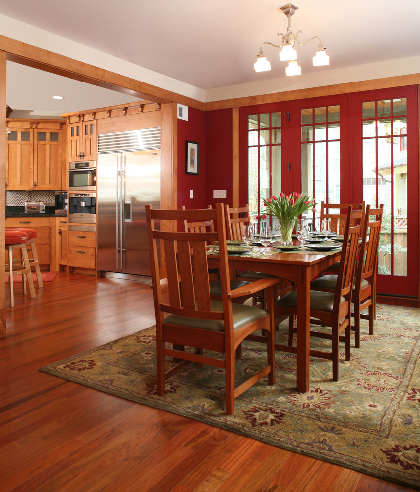 Exemple d'une salle à manger ouverte sur la cuisine craftsman avec un mur rouge et parquet foncé.