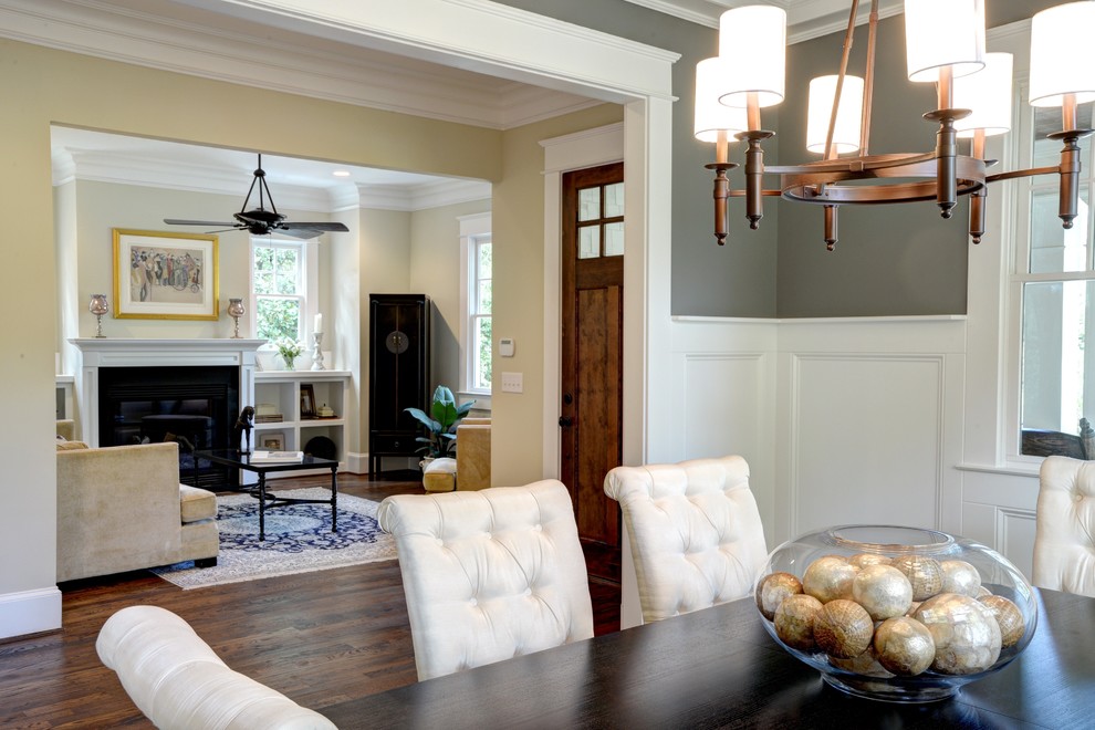 Example of a large arts and crafts medium tone wood floor dining room design in Atlanta with gray walls, a standard fireplace and a wood fireplace surround