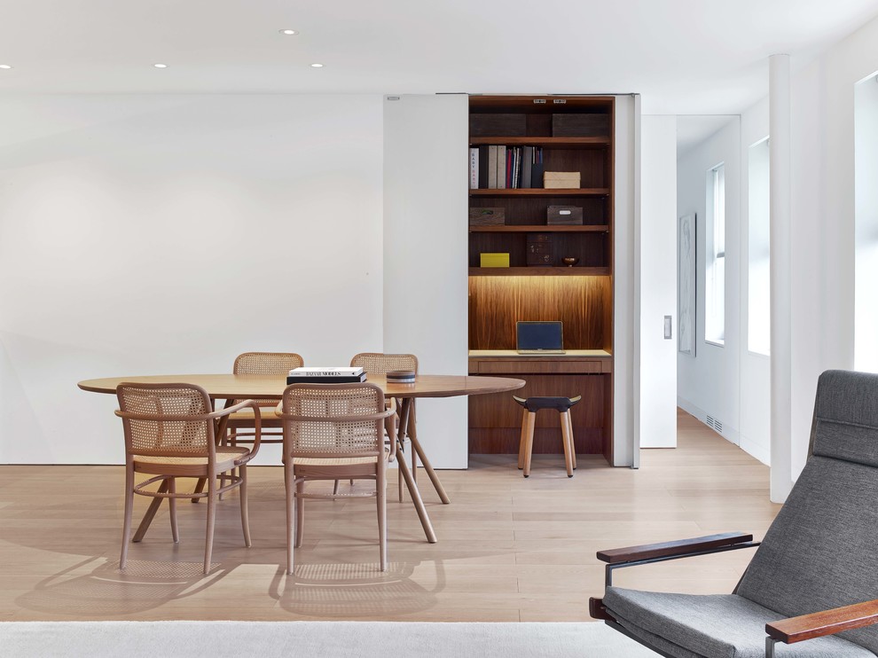 Modelo de comedor minimalista con paredes blancas, suelo de madera clara y suelo beige
