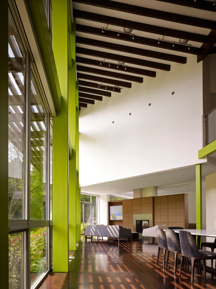 Cette image montre une grande salle à manger ouverte sur le salon design avec un mur vert, un sol en vinyl, une cheminée double-face et un sol marron.