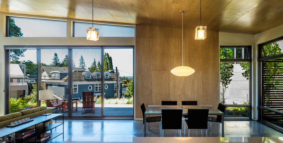 Cette photo montre une salle à manger ouverte sur le salon tendance de taille moyenne avec sol en béton ciré, aucune cheminée, un sol gris et un mur beige.