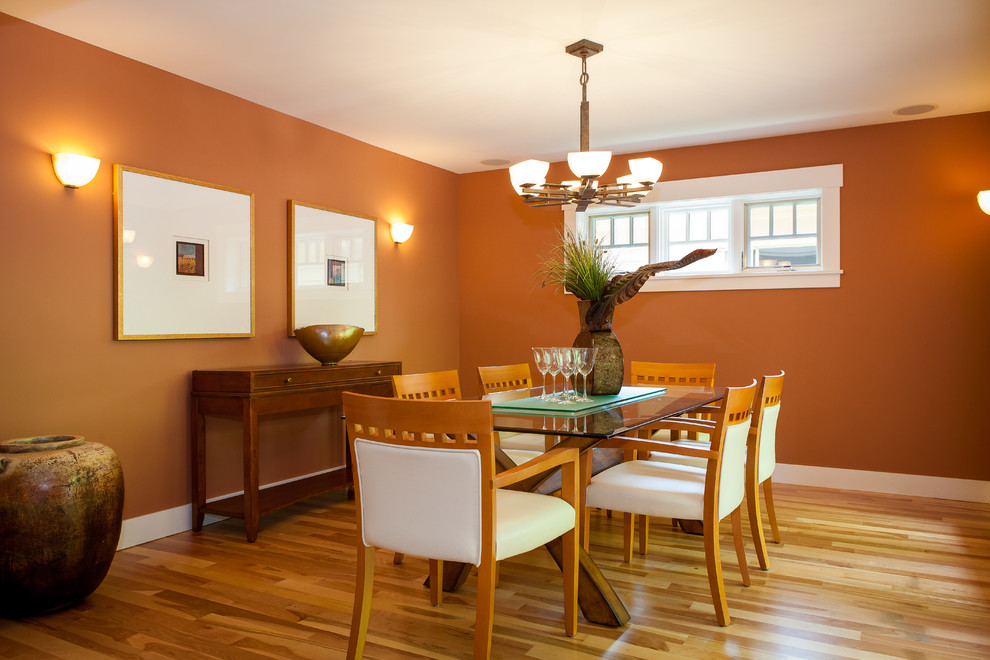 Ejemplo de comedor contemporáneo de tamaño medio cerrado sin chimenea con parades naranjas, suelo de madera en tonos medios y suelo marrón
