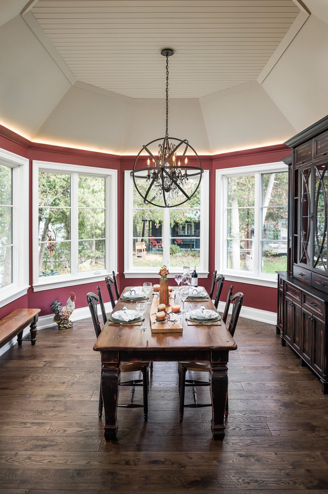 Foto di una sala da pranzo rustica con pareti rosse, pavimento in legno massello medio e pavimento marrone