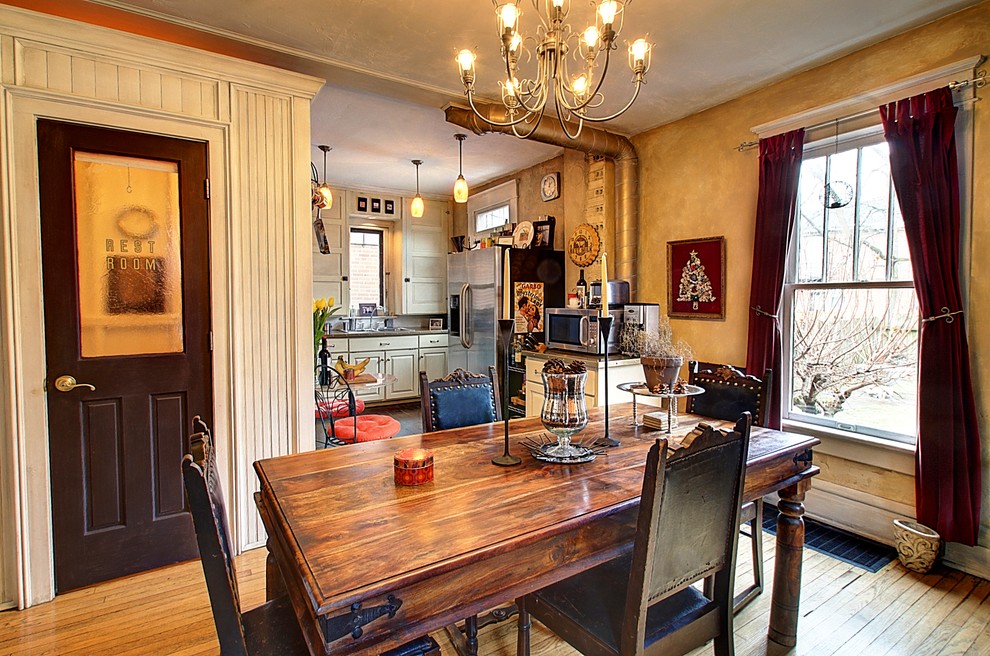 Foto di una sala da pranzo aperta verso la cucina stile rurale con pavimento in legno massello medio e pareti beige