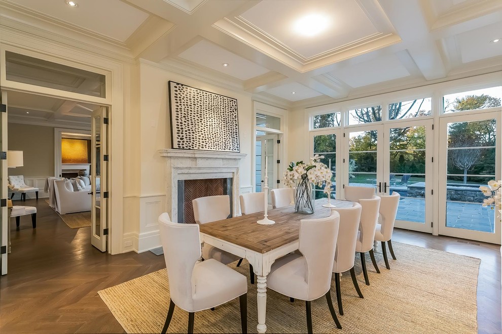 Inspiration for a classic dining room in New York with beige walls, dark hardwood flooring, a standard fireplace, brown floors and feature lighting.