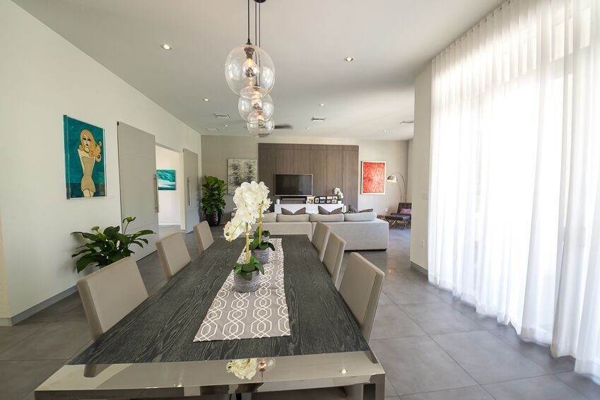 Cette image montre une salle à manger ouverte sur le salon design avec un mur beige, un sol en carrelage de porcelaine et un sol gris.