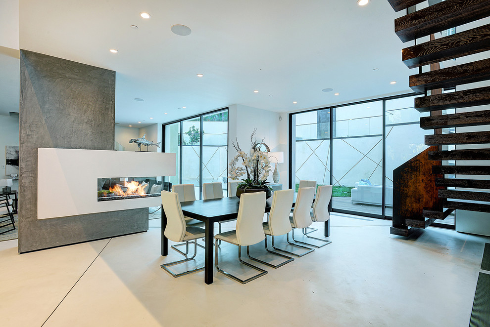 На фото: гостиная-столовая в современном стиле с белыми стенами и двусторонним камином с