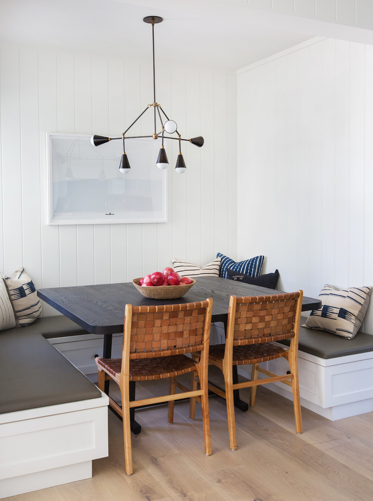 Cette image montre une salle à manger ouverte sur la cuisine traditionnelle avec un mur blanc et parquet clair.
