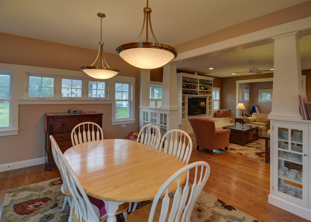 Exemple d'une salle à manger ouverte sur la cuisine craftsman de taille moyenne avec un mur beige et un sol en bois brun.